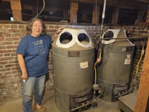 Consuelo Woodhead posing with her historic 1908 Gleewood Gas Furnace in a Pasadena basement before replacement