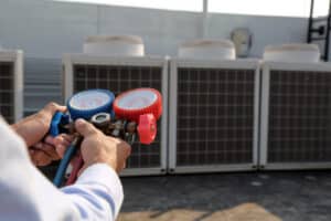 Commercial HVAC technician conducting summer peak demand preparation maintenance on a rooftop unit in Los Angeles